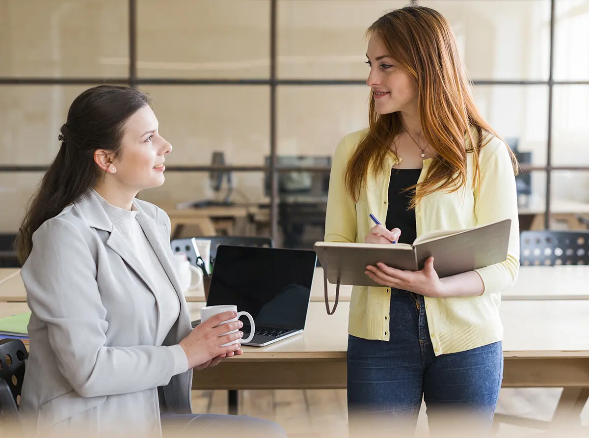 Duas mulheres conversando sobre negócios como consultoria comercial.