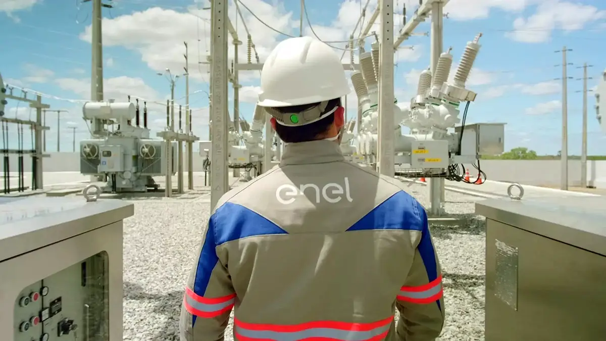 Foto de homem profissional eletricista da Enel andando em pátio externo.