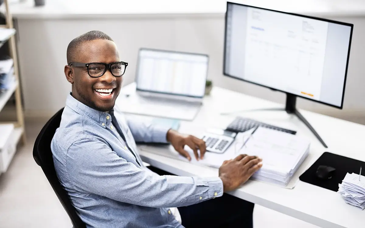 Foto de homem sorridente trabalhando em um escritório como assistente financeiro.
