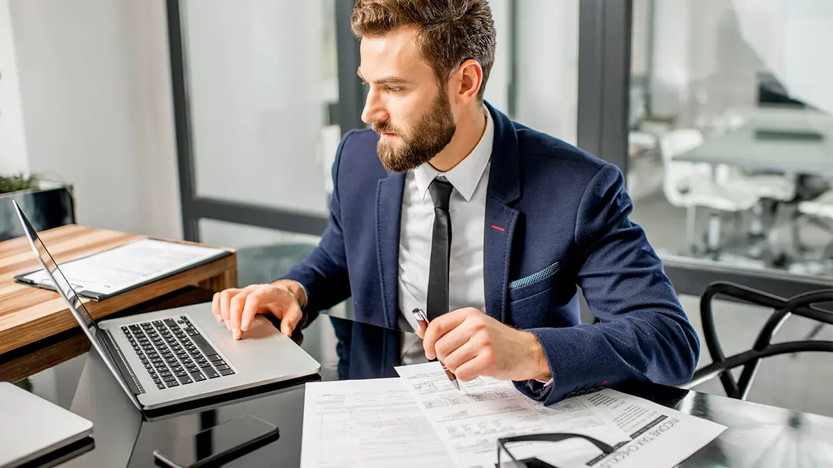 Foto de um homem trabalhando em um escritório e digitando em um notebook.